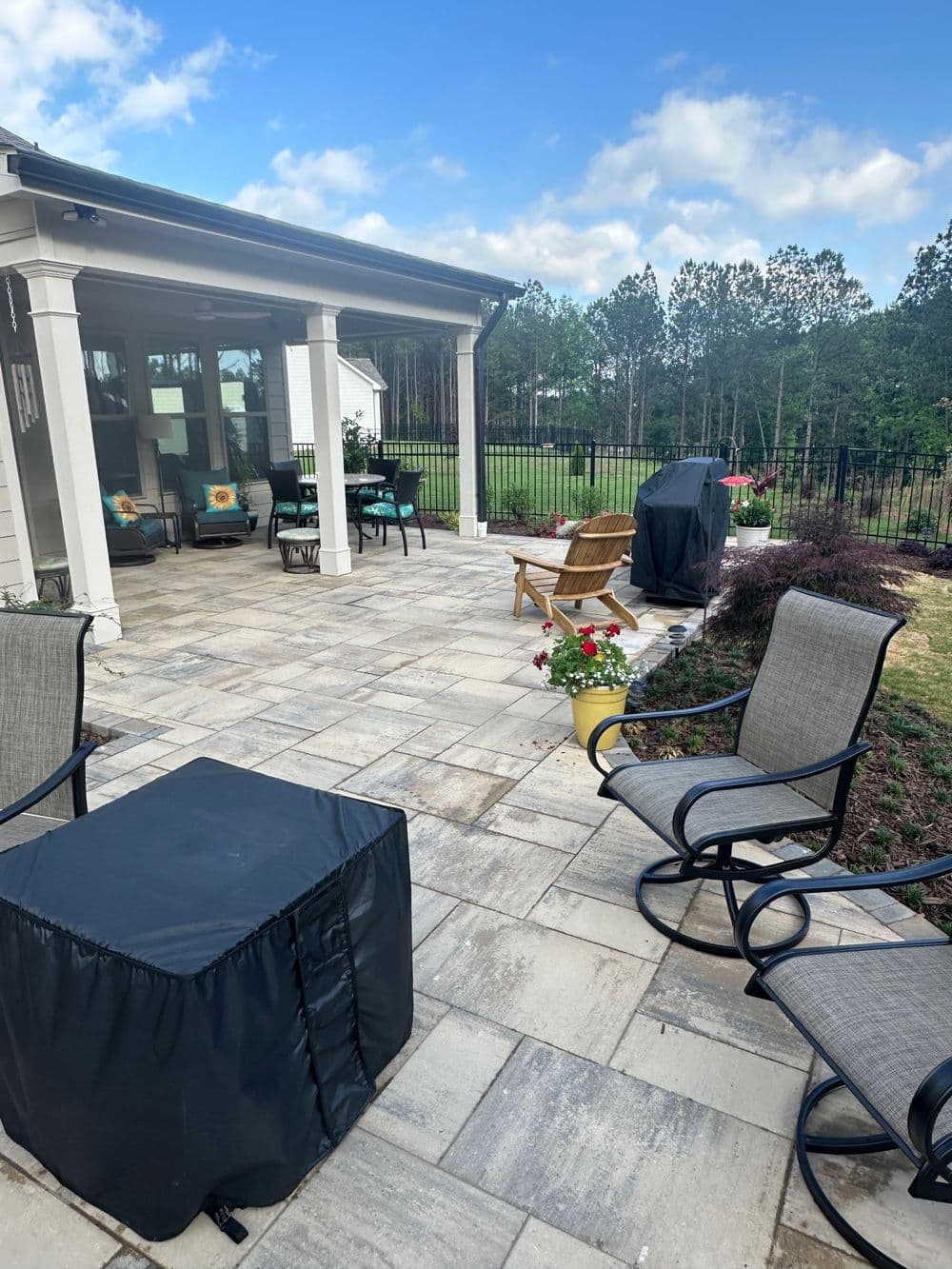 patio seating area with chairs and decorative plants, surrounded by greenery and fence
